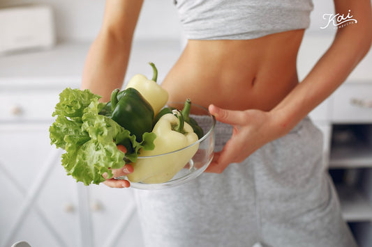 Woman holding a bowl of fresh peppers and lettuce in a bright kitchen — 5種改善便秘的天然方法 · Natural ways to relieve constipation